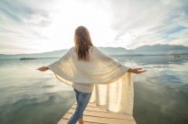 stock-photo-81087857-young-woman-stands-on-pier-arms-outstretched-relaxes